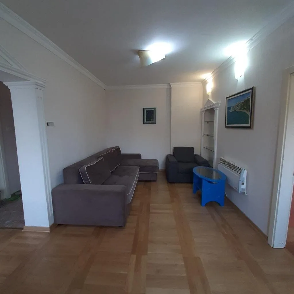 Dnevna soba sa garniturom za sjedenje i drvenim podom.