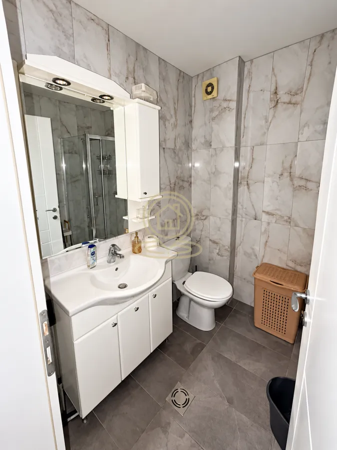 Modern bathroom equipped with a washbasin, toilet, and shower cabin.