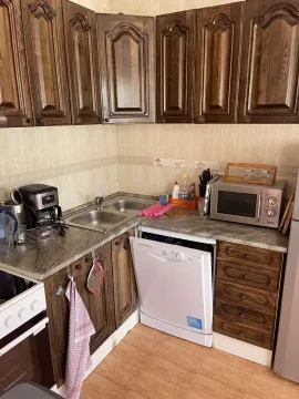 Kitchen with wooden cabinets, a dishwasher, and a microwave. - image 4