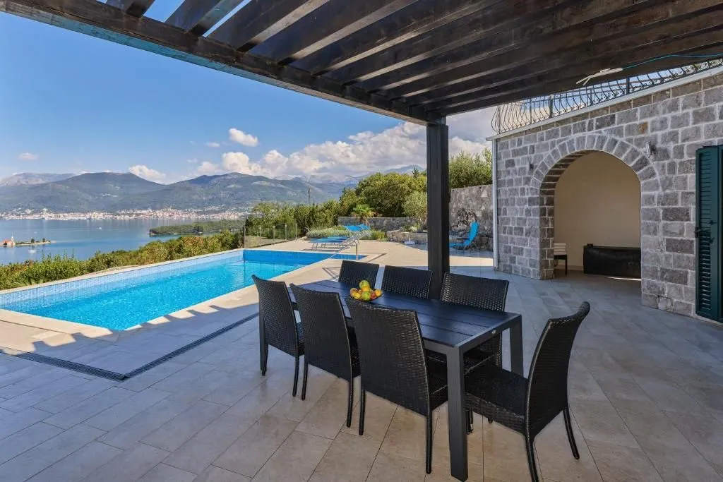 Covered terrace with a dining table and views of the pool and the sea.