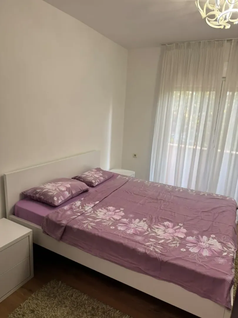 Bedroom with a double bed and a window with white curtains.