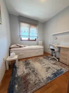 Furnished bedroom with a bed, desk, and rug. - image 10