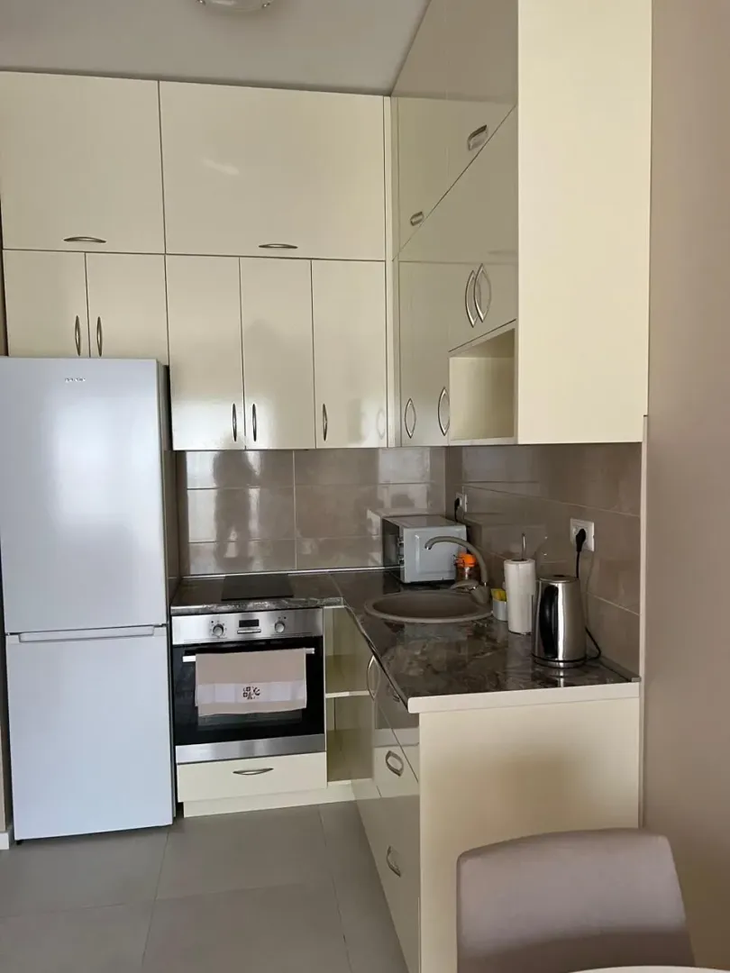 Small kitchen with white cabinets, refrigerator, and built-in oven.