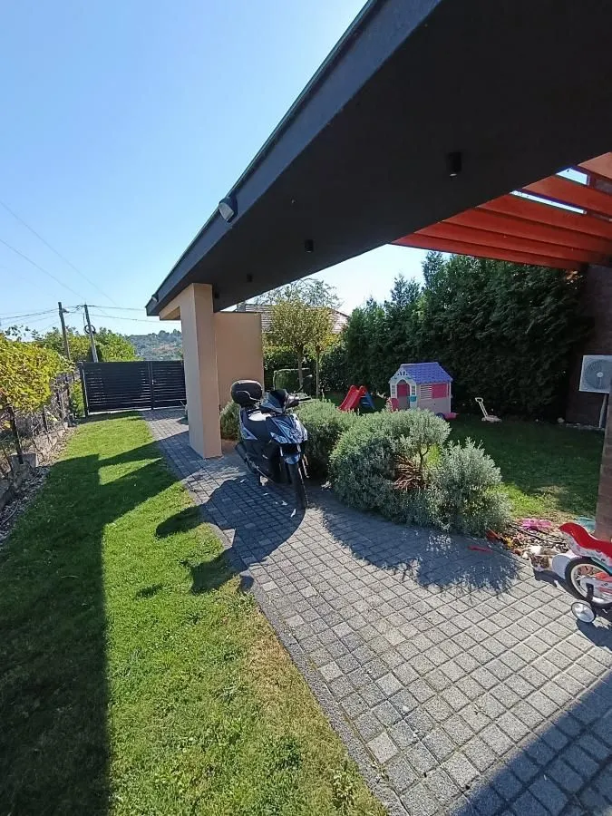 House yard with a paved path, covered area, and green space.