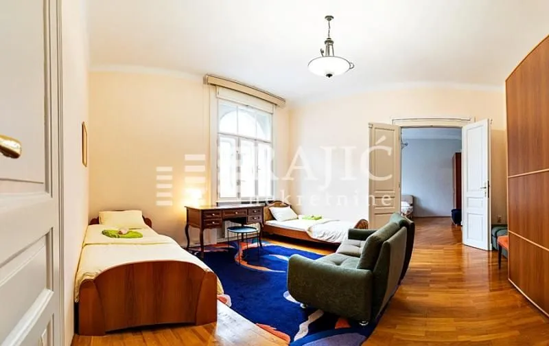 Spacious bedroom with two single beds and a sofa.