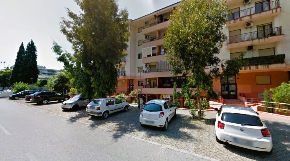 Exterior of an apartment building with parking and greenery.