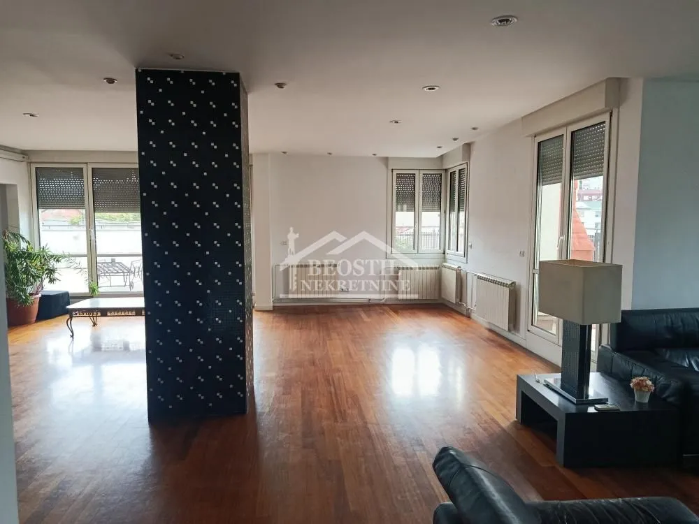 Spacious living room with wooden flooring and large windows.