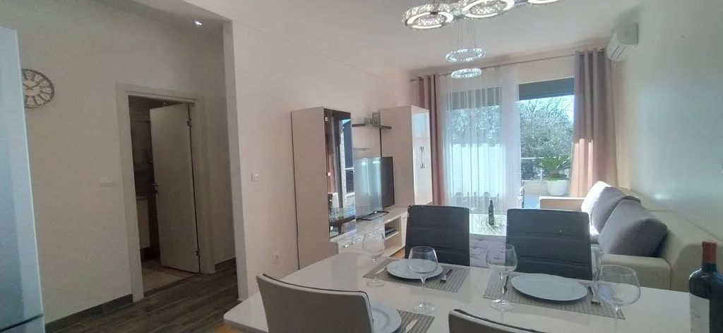 Svijetao dnevni boravak sa trpezarijskim stolom i modernim namještajem.