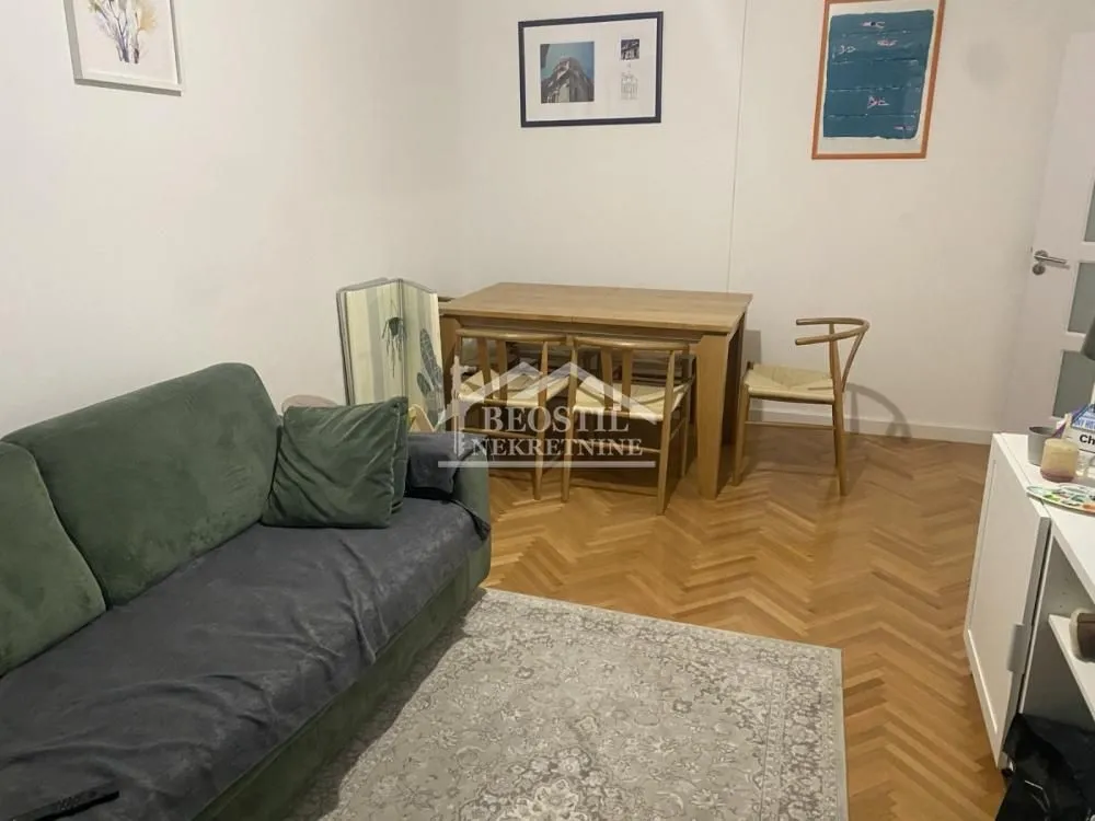 Living room with a sofa, dining table, and parquet flooring.