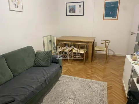 Living room with a sofa, dining table, and parquet flooring. - image 2