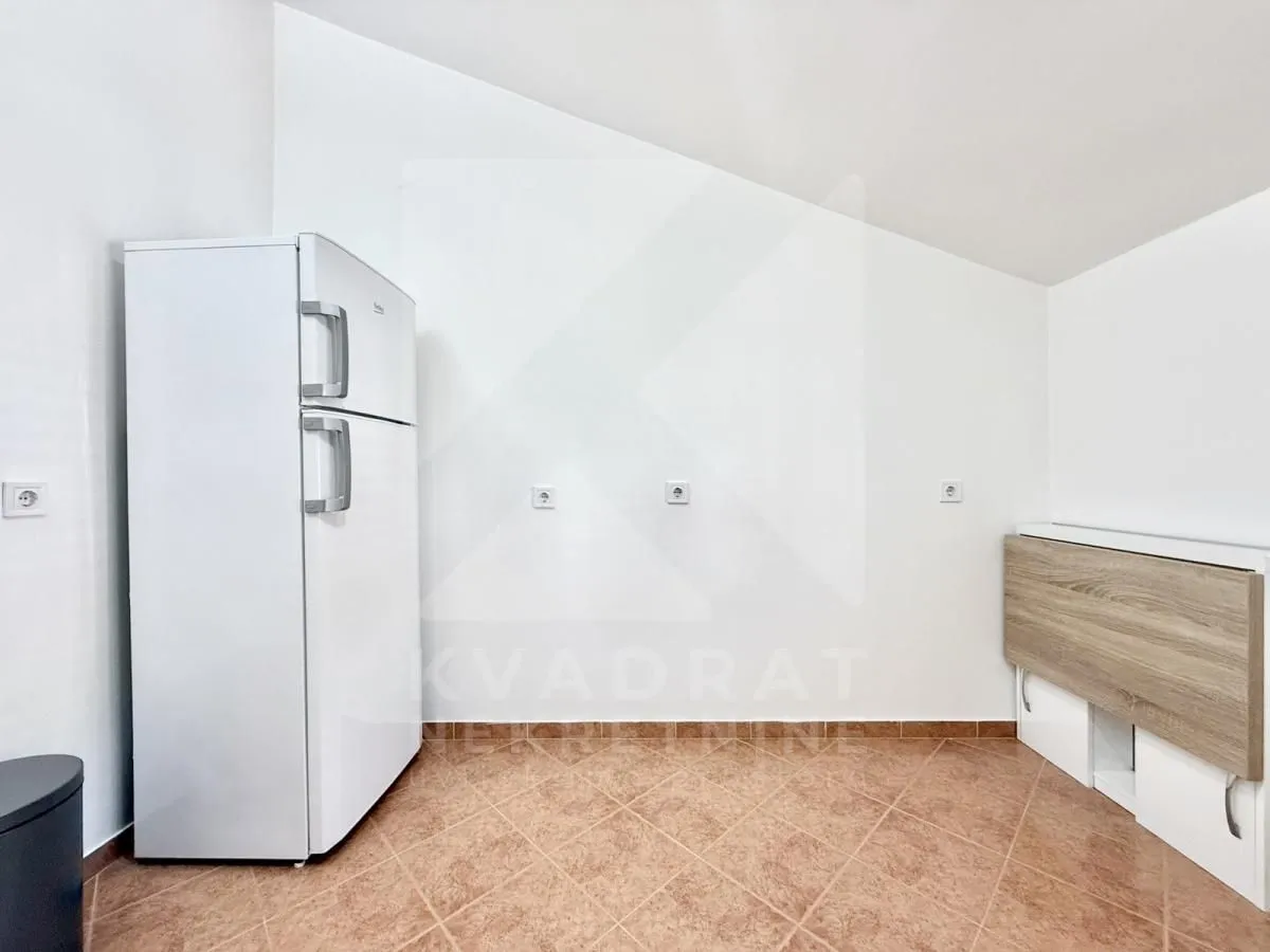 Part of the kitchen with a white refrigerator and ceramic floor tiles.