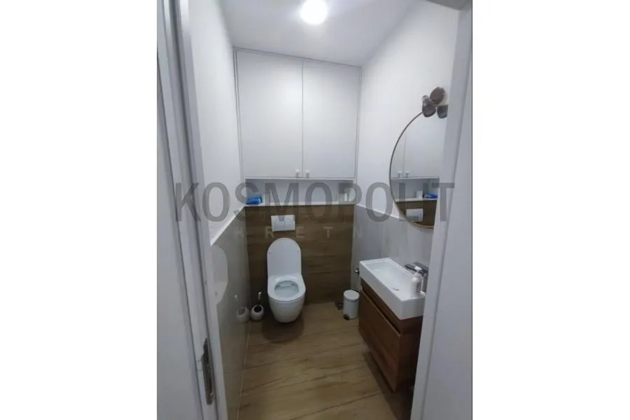 Manje kupatilo sa WC šoljom, umivaonikom, ogledalom i ugradnim ormarićem.
