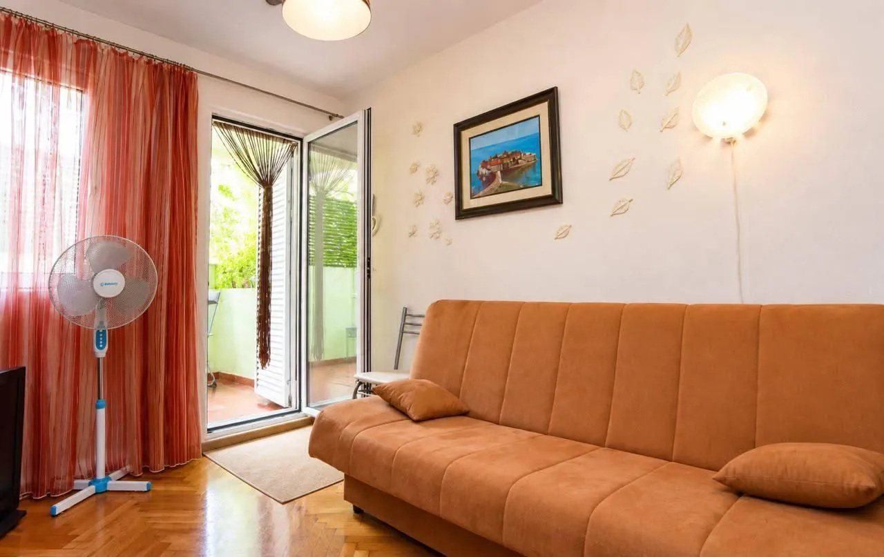 Living room with an orange couch, fan, and access to the terrace.