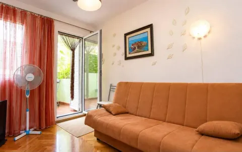 Living room with an orange couch, fan, and access to the terrace. - image 2