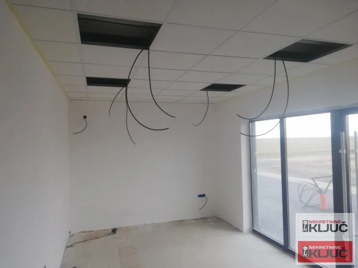 Unfurnished room under renovation with a drop ceiling and large windows.