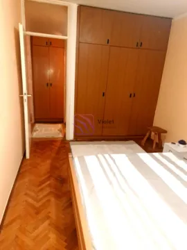 Spavaća soba sa bračnim krevetom, drvenim ormarom i parketom na podu. - image 7