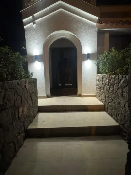 Osvijetljeni ulaz u kuću sa stepeništem i kamenim zidovima noću. - image 2