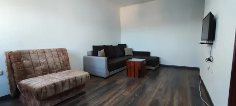 Living room with a corner sofa, an armchair, and a wall-mounted TV. - image 7