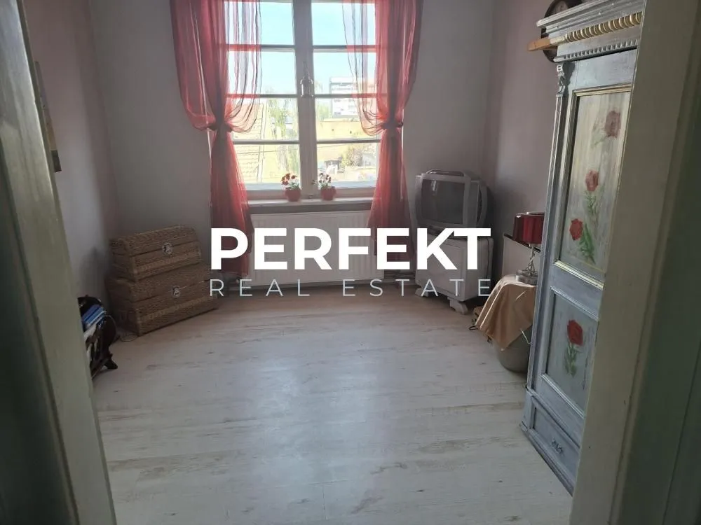 Manja soba sa prozorom, drvenim podom i ormarom.