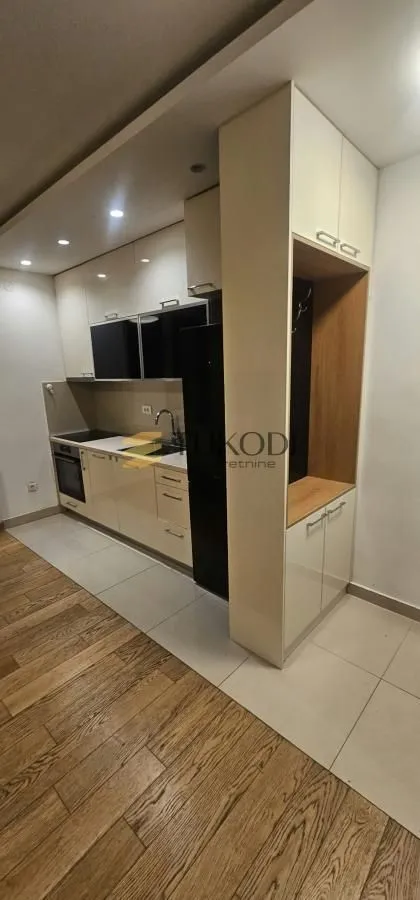 Moderna kuhinja sa ugrađenim elementima i kombinacijom drvenih i keramičkih podova.