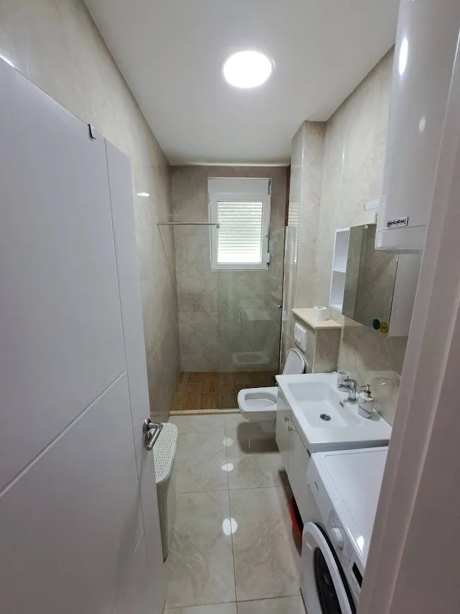 Moderno opremljeno kupatilo sa tuš kabinom, umivaonikom i veš mašinom.