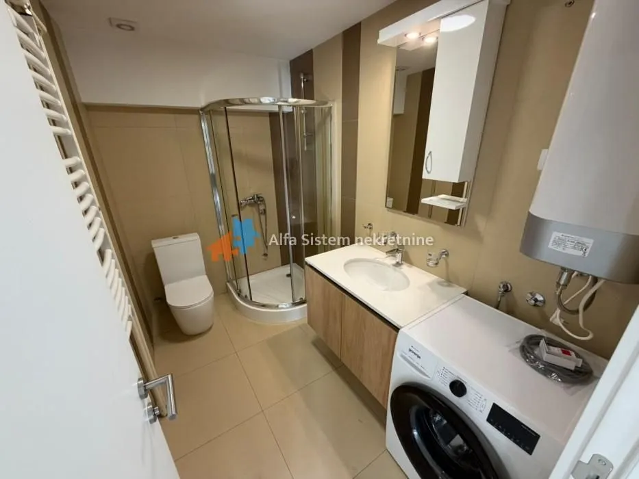 Bathroom with a shower cabin, washbasin, toilet, and washing machine.