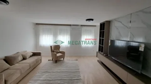 Prostrana dnevna soba opremljena garniturom, foteljom i velikim televizorom. - image 20