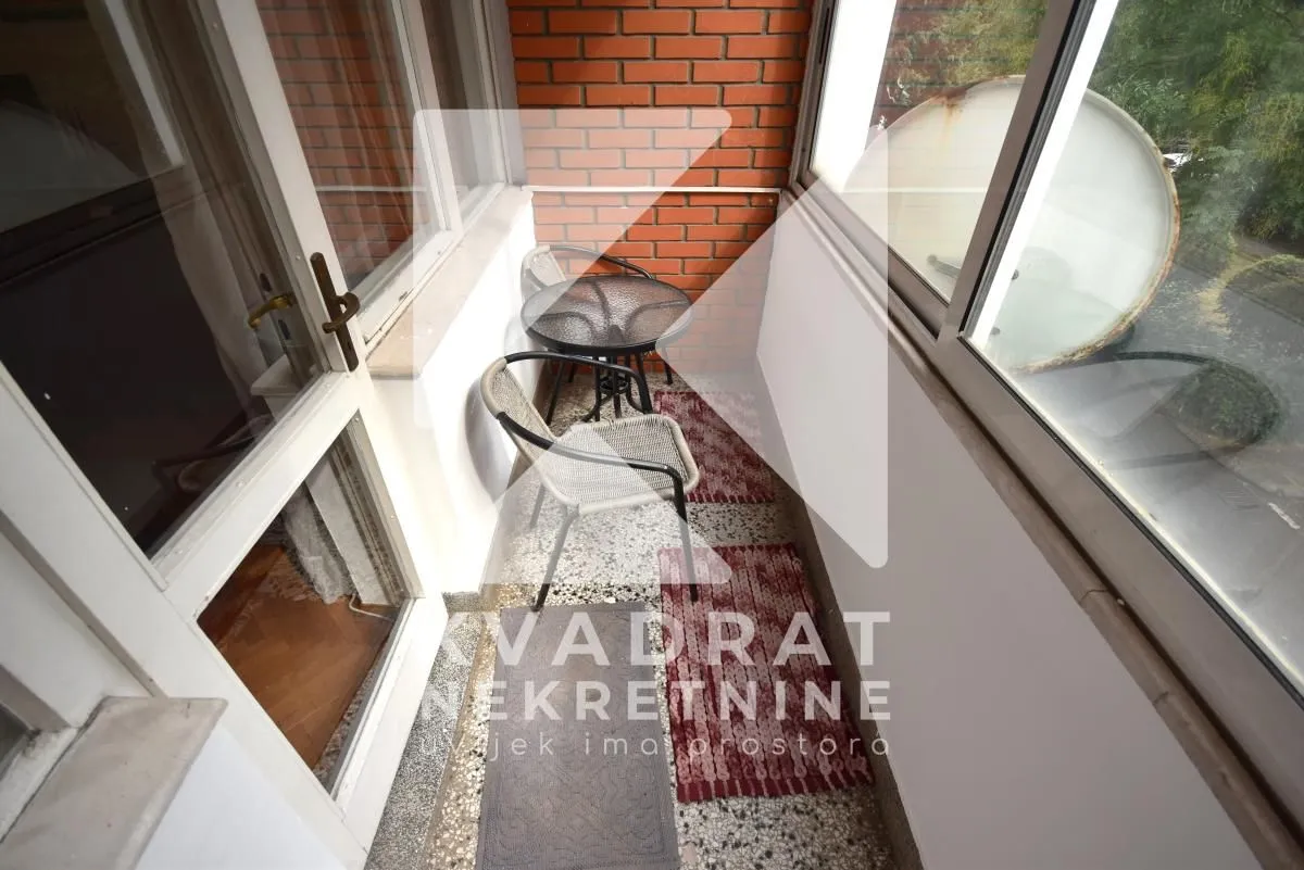 Small enclosed balcony space with glass windows and seating furniture.
