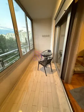 Zastakljeni balkon sa malim stolom, stolicama i pogledom na grad. - image 14