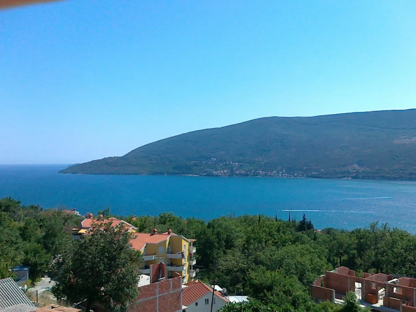 Panoramski pogled na more i planine sa okolnim kućama.