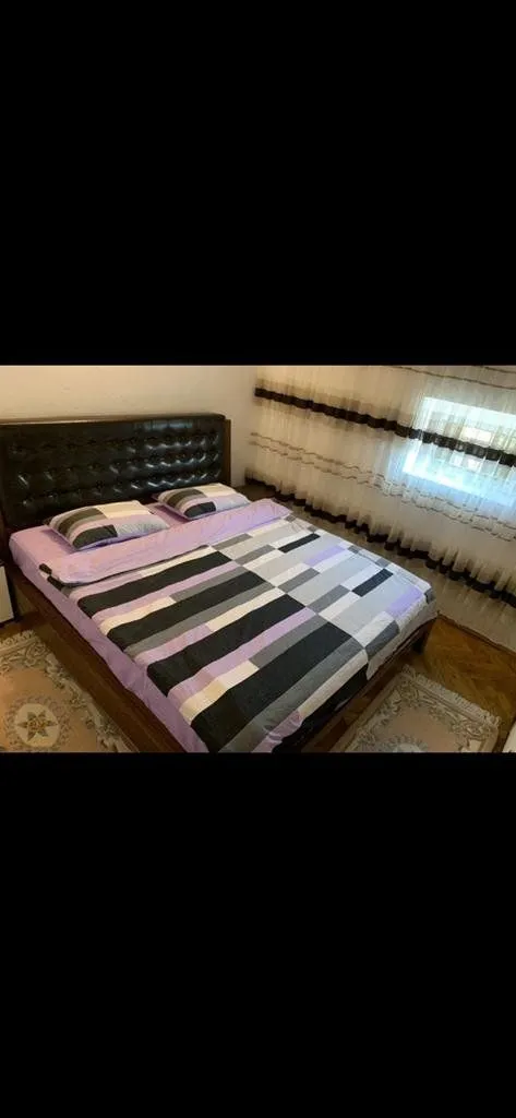 Bedroom with a large double bed and a window with curtains.