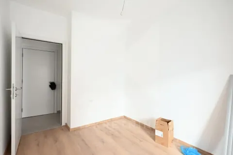 Prazna soba sa bijelim zidovima, drvenim podom i otvorenim vratima. - image 14