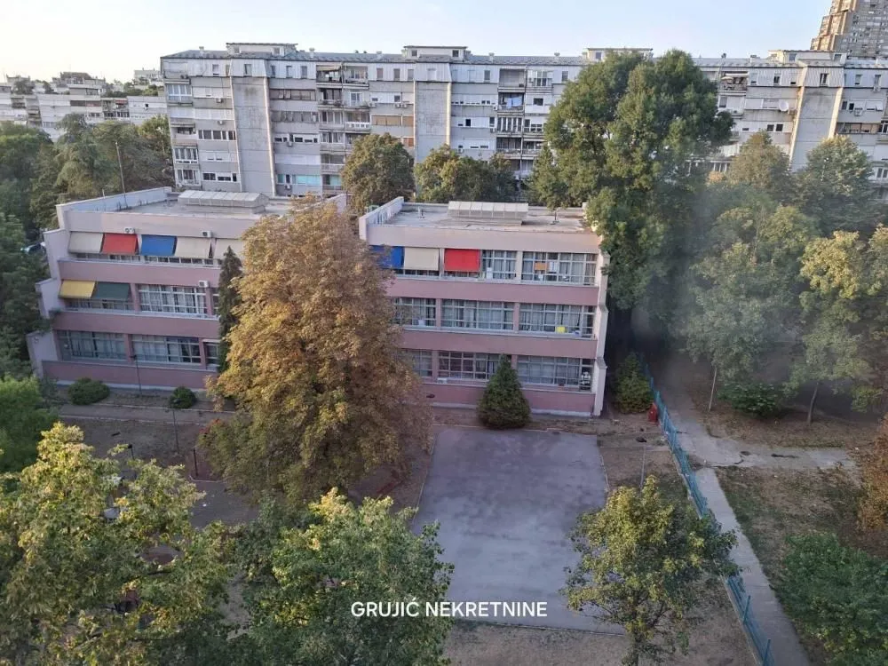 Pogled sa prozora na okolne zgrade i zelene površine.