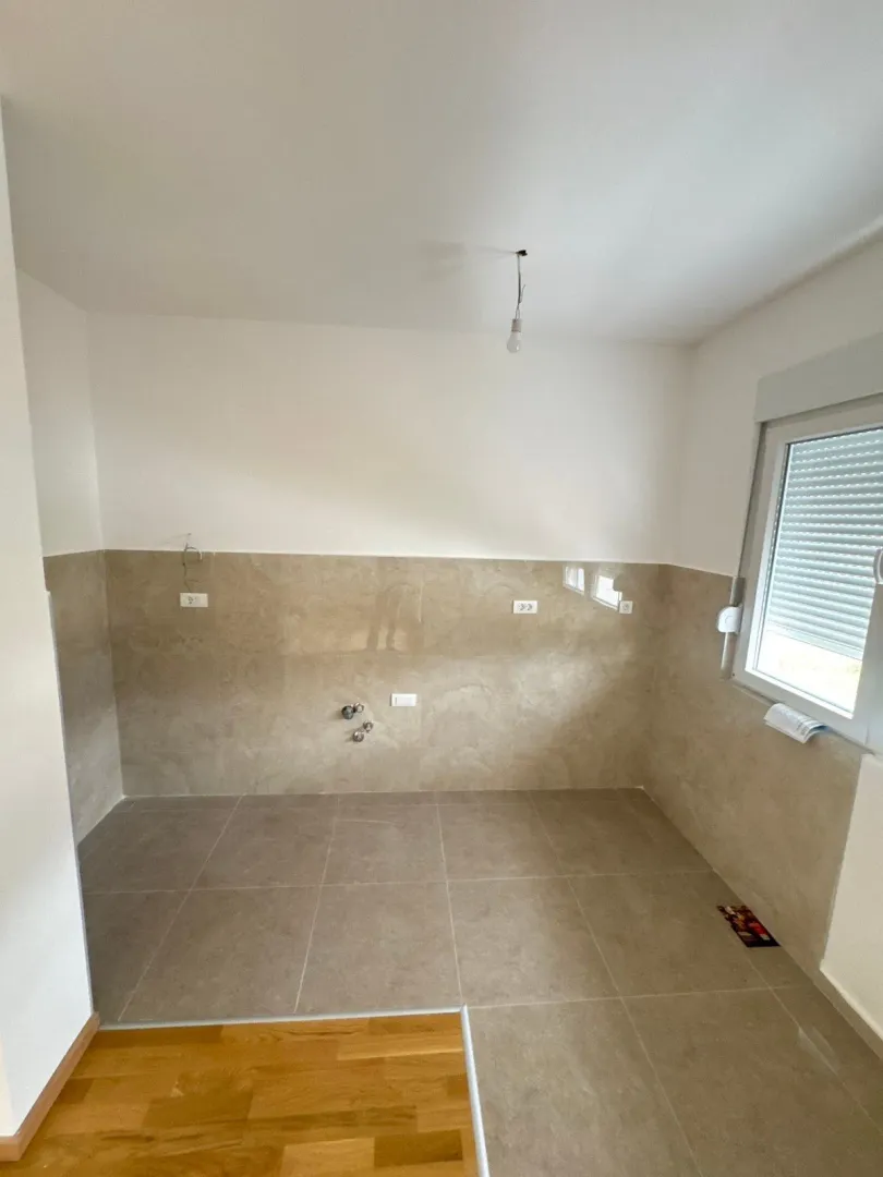 New unfurnished kitchen with ceramic tiles on the wall and floor.