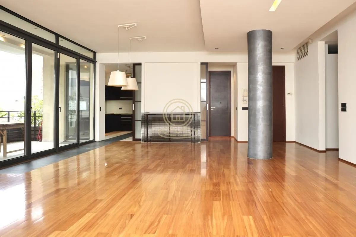 Spacious empty living room with hardwood floors and access to the terrace.