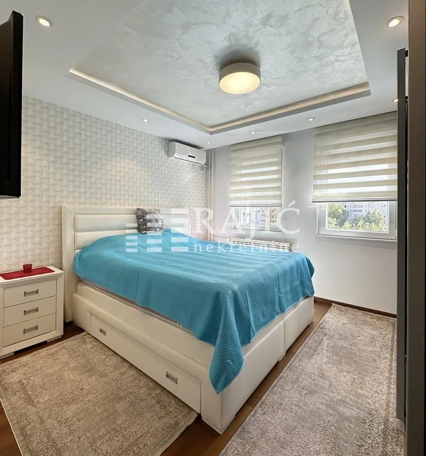 Furnished bedroom with a double bed and a drop ceiling.