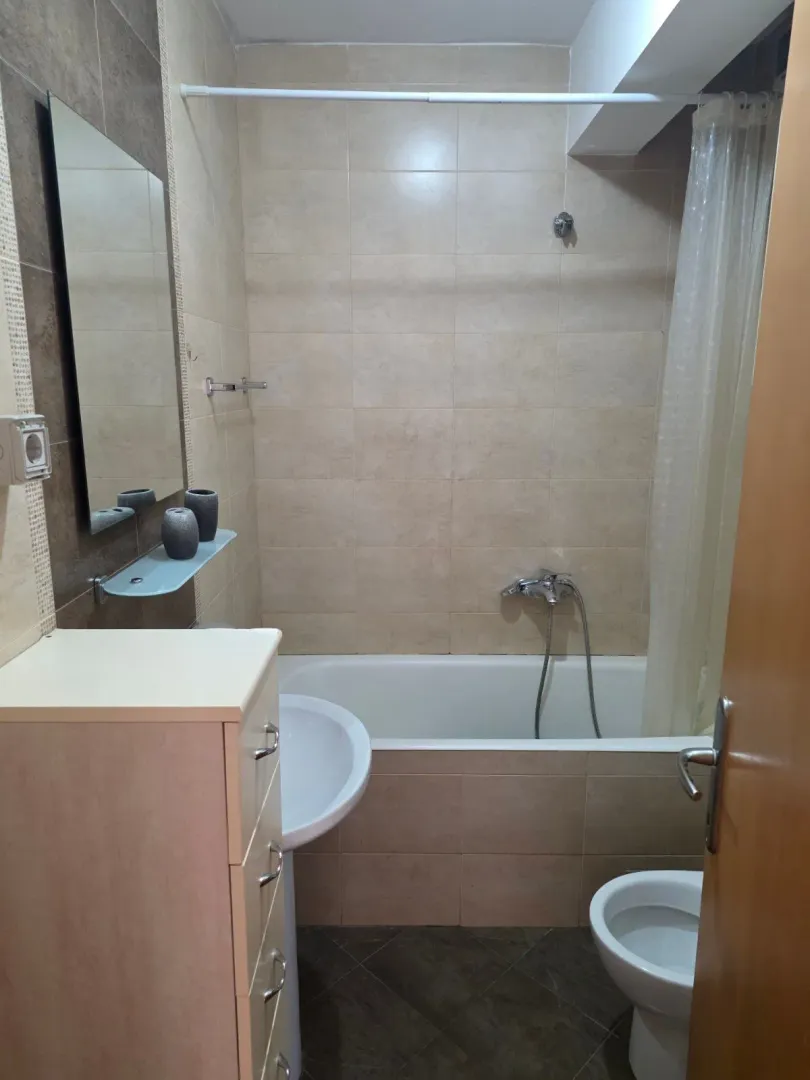 Bathroom with a bathtub, sink, mirror, and toilet.