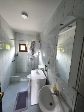 Manje kupatilo obloženo keramičkim pločicama sa tuš kabinom i umivaonikom. - image 6