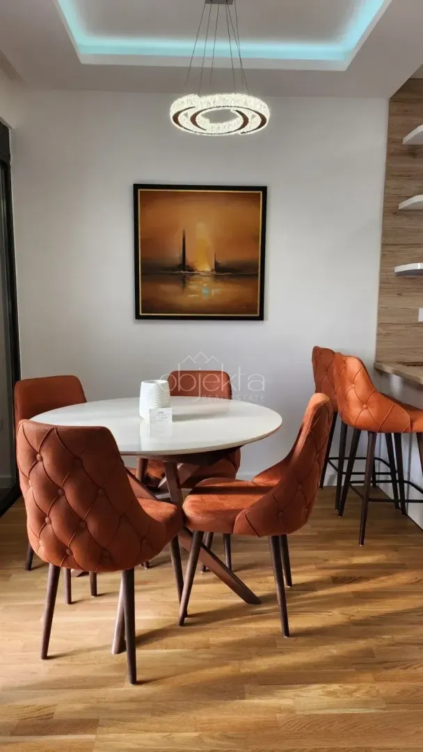 Dining area with a round table and orange upholstered chairs.