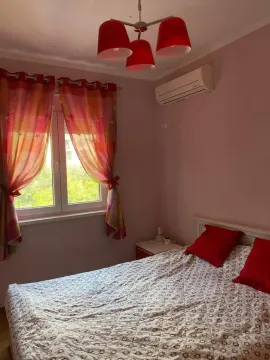 A bedroom with a double bed, red accents, and an air conditioning unit. - image 9