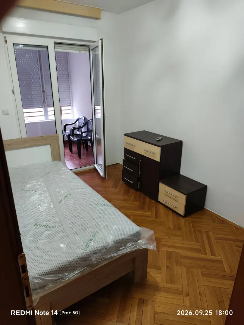 Namještena spavaća soba sa krevetom i komodom, te izlazom na terasu.