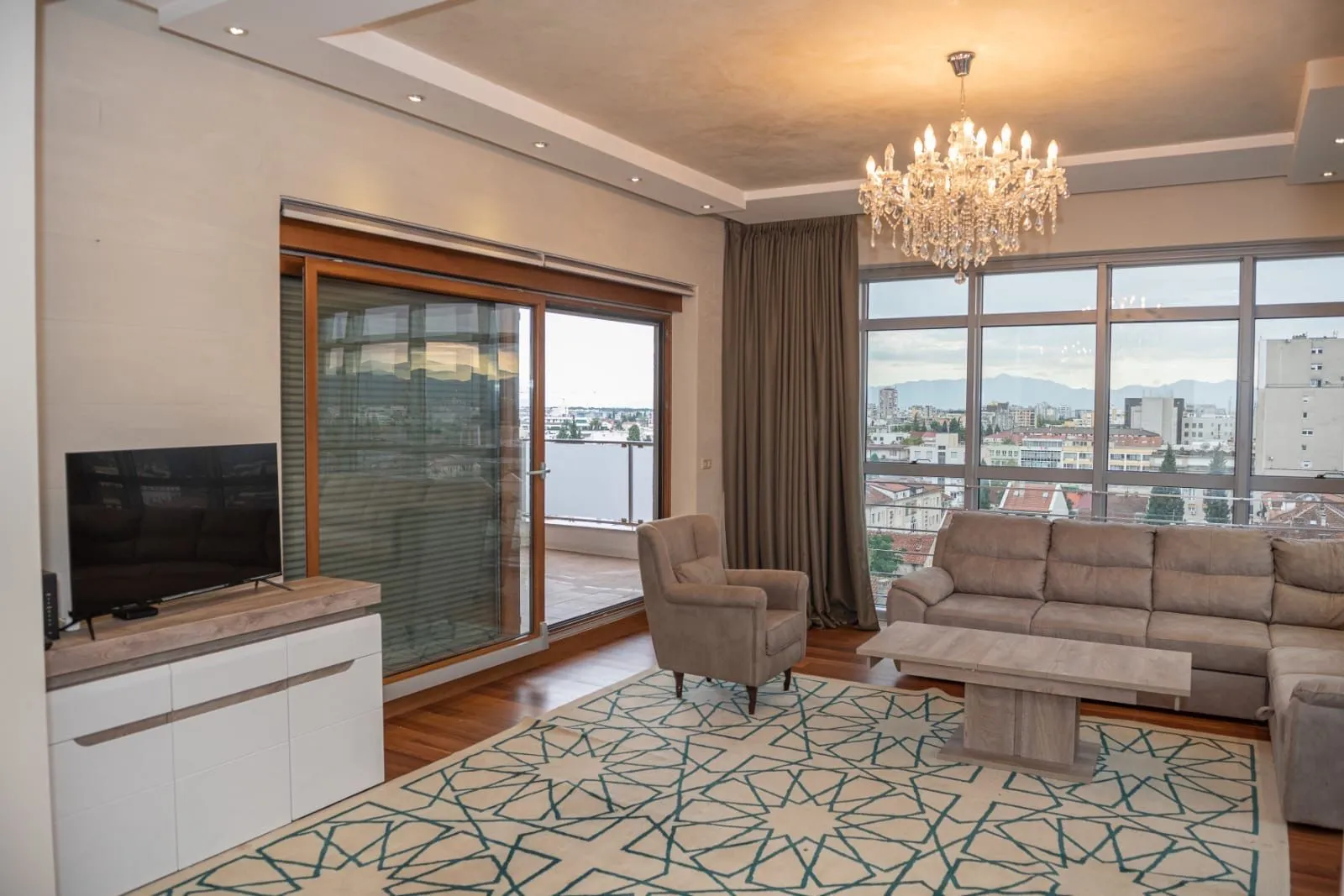 Spacious living room with sofa, TV, and balcony access.