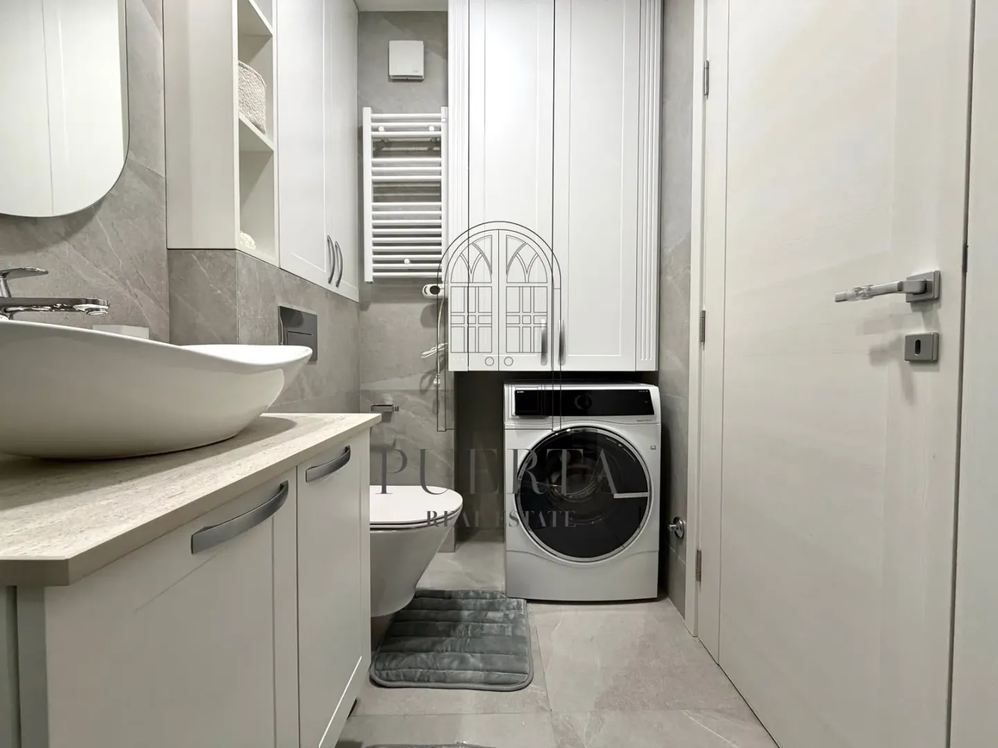 Modernly equipped bathroom with a washbasin, toilet, and washing machine.