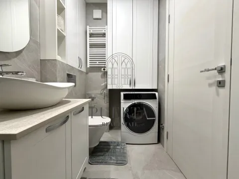 Modernly equipped bathroom with a washbasin, toilet, and washing machine. - image 12