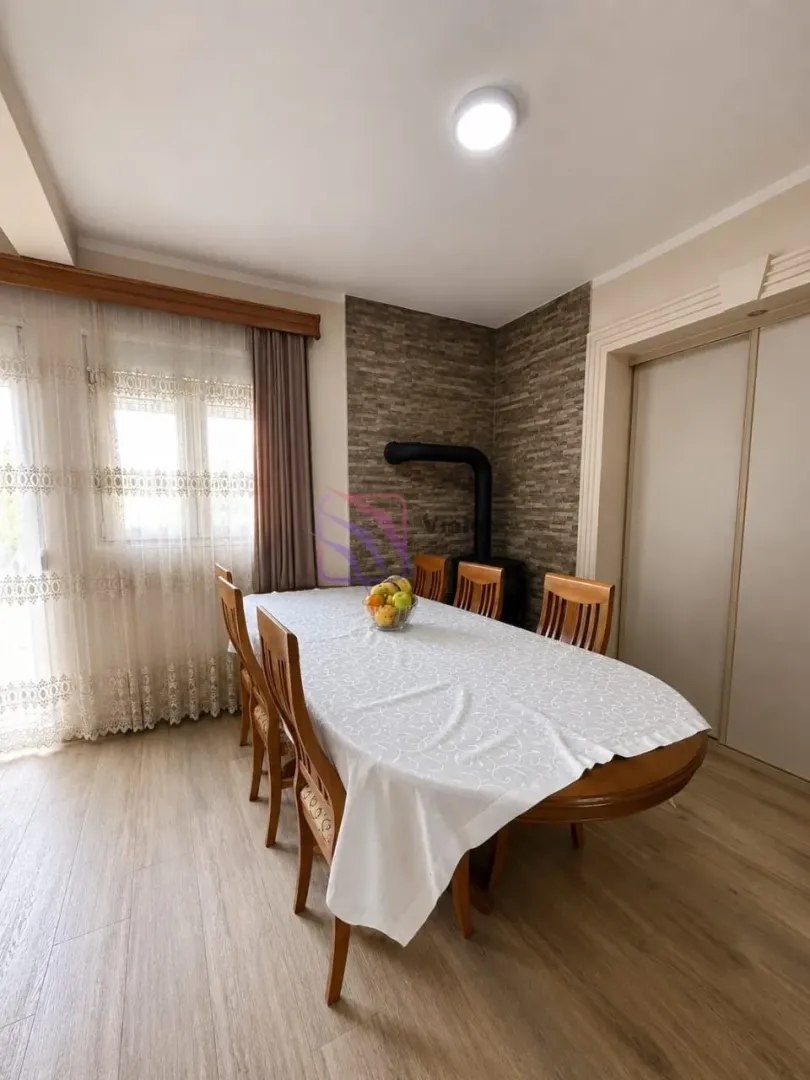 Dining area with a large table and wooden chairs near the window.