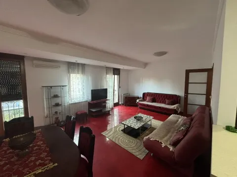 Spacious living room with a red floor, seating set, and dining table. - image 2