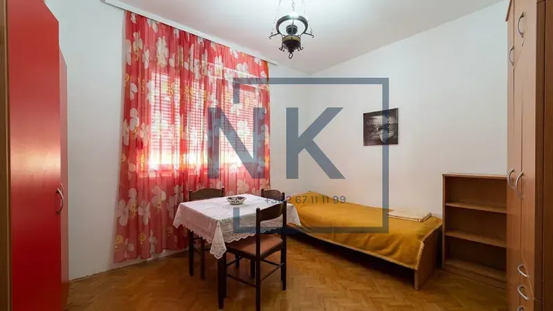 Smaller bedroom with a bed, table, and wardrobe.
