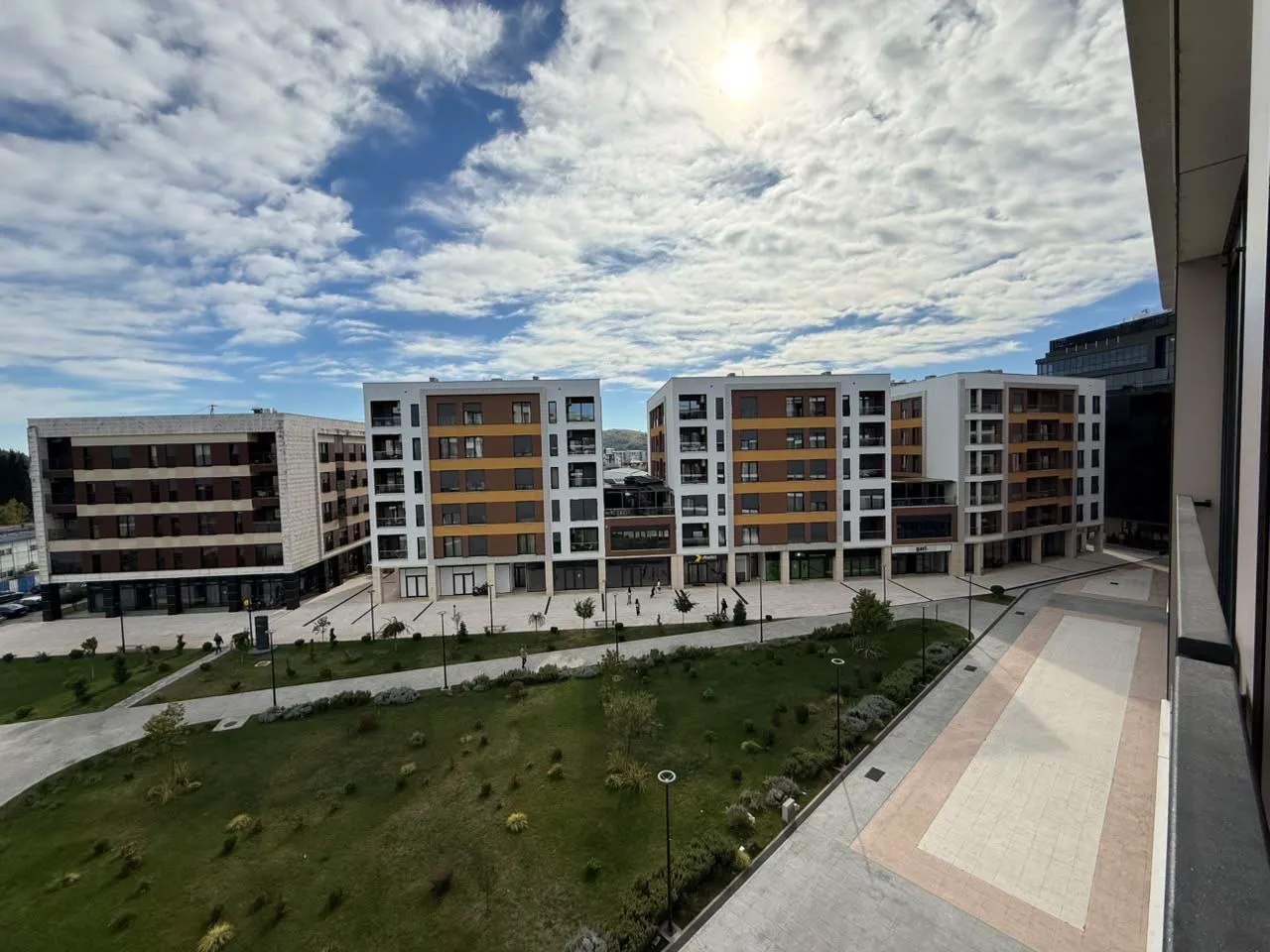 Pogled sa terase na uređeno dvorište i moderne stambene zgrade.