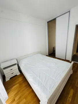 Bright bedroom with a white bed, nightstand, and built-in closet. - image 4