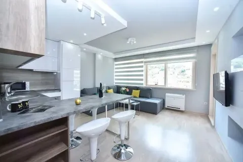 Open-plan living room with a kitchen, breakfast bar, and sofa set. - image 4